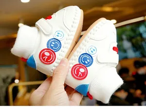Détail de chaussure bébé en cuir PU blanc avec cheville en maille et motif de sourire