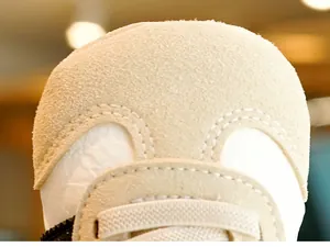 Detailed macro view of soft beige suede baby shoe toe with reinforced double stitching