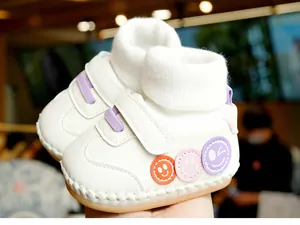 Vue détaillée d'une chaussure bébé blanche avec broderie sourire et fermeture velcro