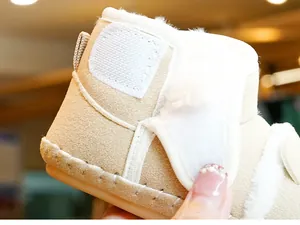 Detail of warm baby snow boots featuring beige suede fabric and white faux fur lining