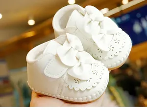 Nahaufnahme von weißen gefütterten Babyschuhen mit Schleifen und Lochmuster-Details