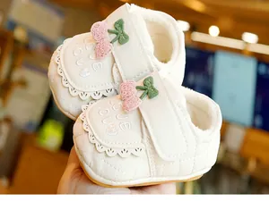 Détail de chaussures bébé avec broderie cerise, lettrage love et doublure en peluche