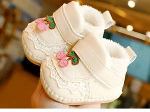 Close-up of warm baby shoes with cherry embroidery, lace trim and plush lining