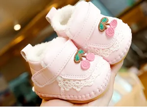 Close-up of pink infant winter shoes with cherry embroidery, lace trim, and warm fleece lining
