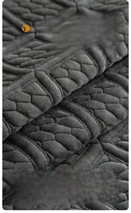 Detail of dark gray milk velvet sofa cushion with quilted hexagon texture and thick plush