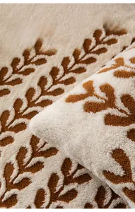 Détail de la housse de canapé en polaire épaisse avec motif de feuilles brunes