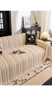 Detail of cream striped sofa throw cover featuring soft fringe edges and a textured finish