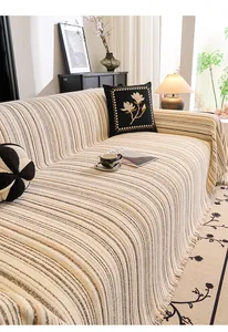Detailed view of beige striped sofa throw with fringe trim and premium knitted texture