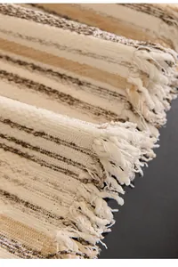 Close-up of woven cream and brown striped sofa cover with fringe details and texture