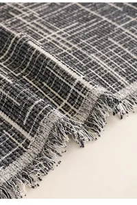 Close-up of luxury black and white checkered sofa throw fabric with tassel fringe detail