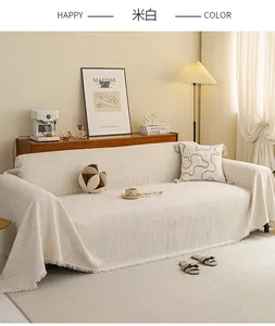 Close-up of cream textured sofa cover with decorative tassels in a cozy home setting