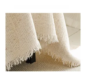 Close-up of cream textured sofa cover featuring woven flecks and fringe details
