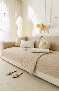 Close-up of beige quilted sofa cover with chevron texture and matching throw pillows
