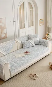 Close-up of blue floral chenille sofa cover fabric with decorative white pom-pom edges