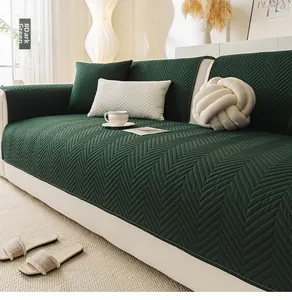 Detail of dark green quilted sofa cover with herringbone stitching on white leather couch