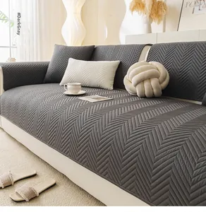 Detail of dark gray quilted sofa cover with chevron pattern and non-slip texture