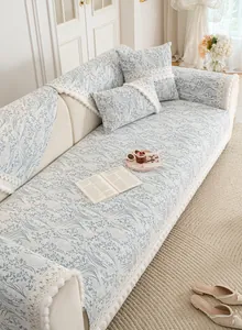 Detail of blue floral chenille sofa cover featuring white lace trim and pom pom fringe