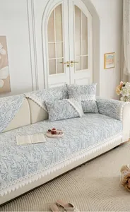 Detail of light blue floral chenille sofa cover with white lace and pompom trim