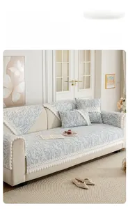 Detail of floral chenille sofa cover with white lace edges and soft pom-pom fringe accents