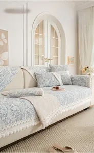 Detail of chenille sofa cover with floral pattern and decorative lace pom-pom fringe