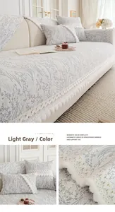 Detail of light gray chenille sofa cover with white lace trim and decorative pom-poms