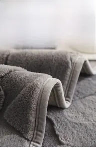 Detail of grey rabbit faux fur sofa cover with wide ribbon edging and thick plush texture