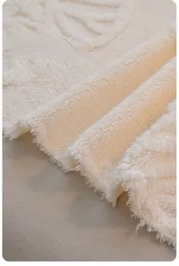 Close-up of thick beige plush sofa throw featuring soft wavy texture and tassel fringe