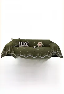 Close-up of thick velvet sofa cover with white heart and swan patterns in dark green