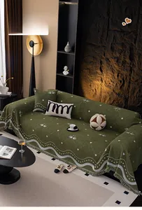 Close-up of heavy chenille sofa cover with dark green swan patterns and fringed edges