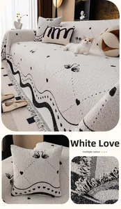Detail of white chenille sofa cover with tassels, black swan patterns and heart motifs