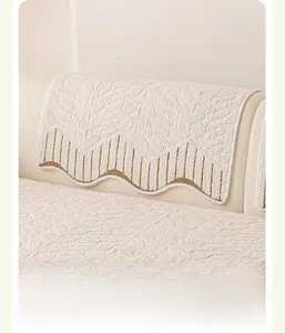 Close-up of cream sofa cover with embossed texture and brown wavy embroidered edges