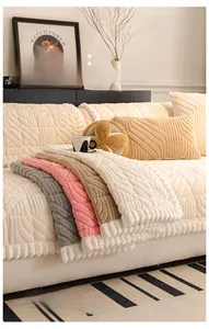 Detailed view of quilted velvet sofa cover with geometric textures and fringe trim