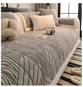 Close-up of gray plush sofa cover with leaf pattern texture and white pom-pom trim