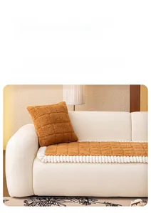Detailed view of caramel sherpa sofa cushion with square texture and white pom-pom trim