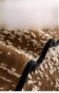 Detail of the widened black edge piping on a thick brown and white plush sofa cover