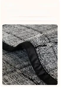 Detail of wide-bordered edges and textured woven fabric on plush grey sofa cover