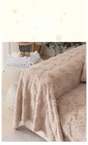 Detail of beige faux rabbit fur sofa cover with Christmas tree pattern and tassels