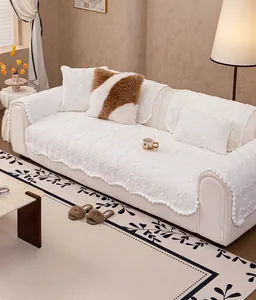 Detailed view of plush cream sofa cover with embossed floral patterns and pom-pom fringe