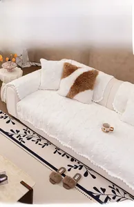 Detail of cream plush quilted sofa cover featuring soft pompoms and thick winter texture