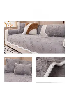 Detail of grey plush sofa cover with floral texture and decorative pom-poms on pillows