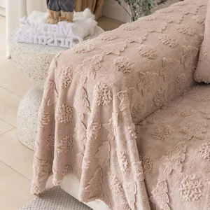 Thick beige plush sofa cover with floral relief texture and decorative fringe detail