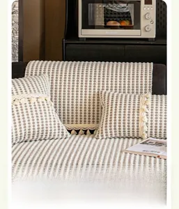 Close-up of beige stripe knit sofa cover with pom-pom fringe and lace border detail