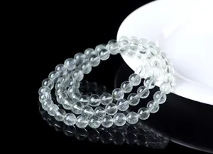 Detalle de pulsera de tres vueltas de cuarzo rutilado verde natural en superficie reflectante