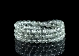 Detalle macro de tres pulseras de cuarzo rutilado verde sobre una superficie negra