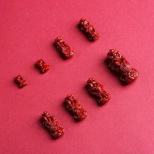 Red Cinnabar Pi Xiu charms with Chinese fortune carvings on a textured red background