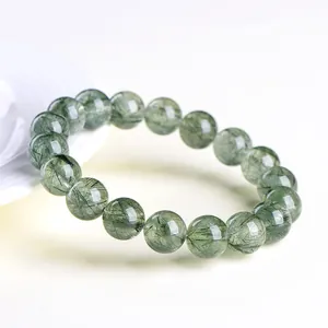 Natural clear green rutilated quartz beaded bracelet on a white porcelain dish