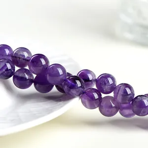 Perle tonde in ametista naturale lucida per gioielli fai-da-te su sfondo ceramica bianca