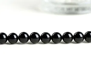 Macro shot of polished black tourmaline beads with high glossy finish and sharp reflection