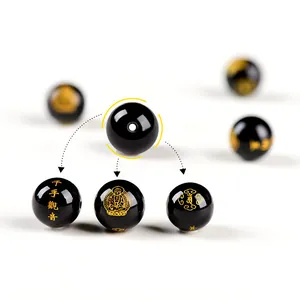 Dettaglio macro di perla in agata nera con incisione dorata Guanyin dalle mille mani e motivi