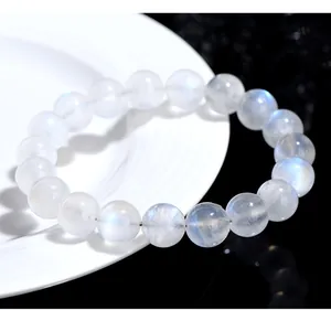 Macro shot of 10mm blue moonstone beads with elegant blue sheen on white ceramic tray